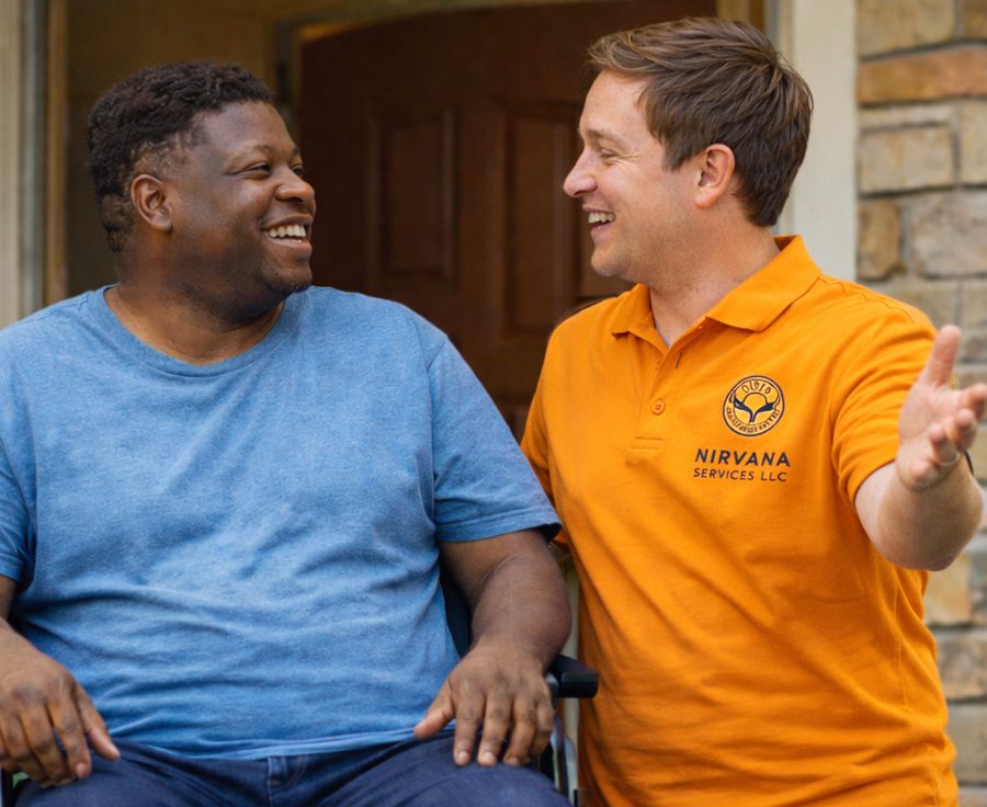 A direct support professional talking with a man who uses a wheelchair outside his front door.